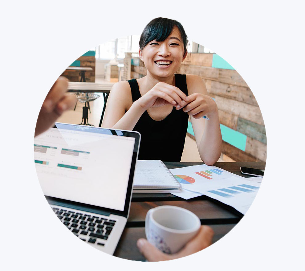 Photo femme souriante à table avec ordinateur et graphiques